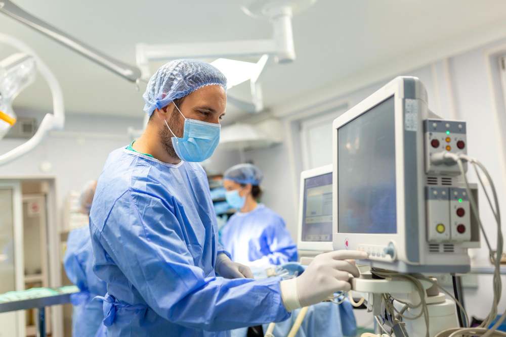 A man in hospital dress, wearng mask playing with medical machine.